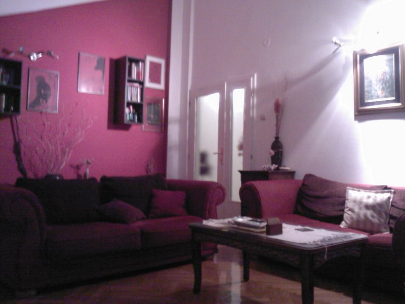 Cozy living room with burgundy sofas and a bright accent wall in an apartment for sale in Budva, Montenegro.