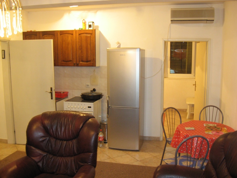Kitchen in an apartment in Budva, Montenegro: wooden cabinets, stove, refrigerator, dining area, and leather chairs.