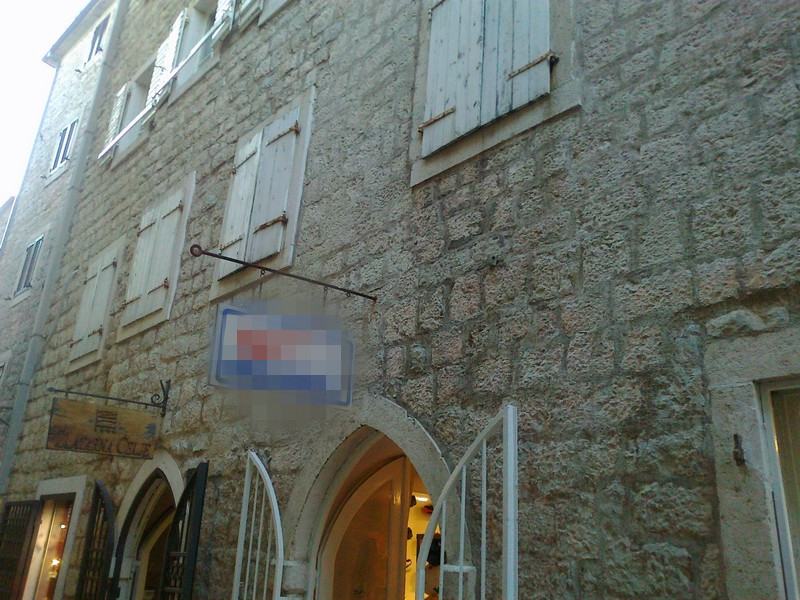 Facade of a historic stone building with wooden shutters in the old town of Budva, Montenegro.
