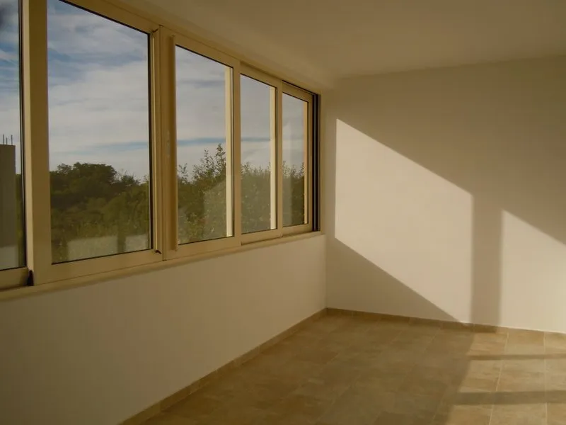 Empty room with tiled floor and large windows overlooking trees. Does not resemble a standard bedroom or living area.