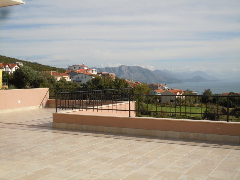 Spacious terrace of a house in Budva, Montenegro, with panoramic views of the sea, mountains, and the city’s tiled roofs.