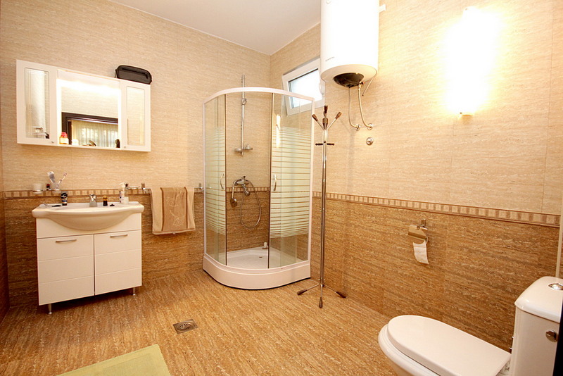 Bathroom with a shower cabin in a house in Sutomore, Montenegro: white fixtures and beige tile finishes.