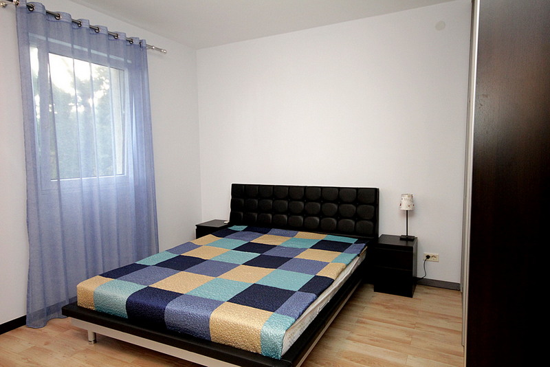 Bright bedroom with a double bed in a house for sale, Sutomore, Montenegro: modern furniture and a view from the window.