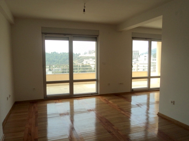 Bright living room with parquet flooring and panoramic windows in an apartment in Bečići, Montenegro.