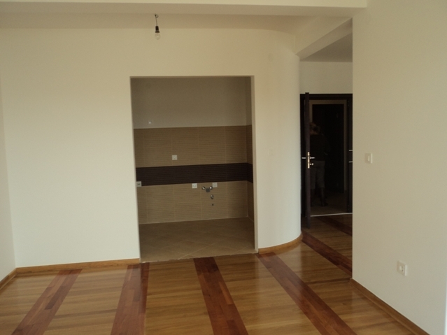 Living room with parquet flooring and kitchen area in an apartment for sale in Bečići, Montenegro. Bright finishes and modern design.