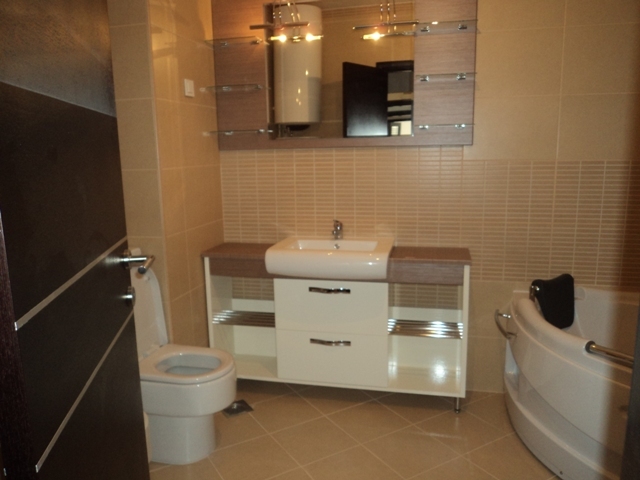 Modern bathroom in an apartment in Bečići, Montenegro: corner bathtub, vanity with sink and mirror.