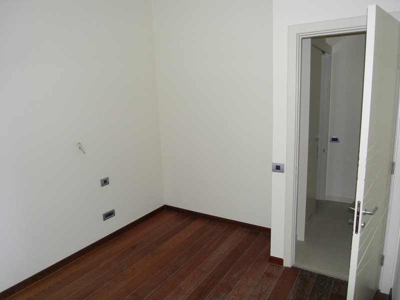 Bright bedroom with parquet flooring and an interior door in an apartment in Budva, Montenegro. Modern interior finishes.