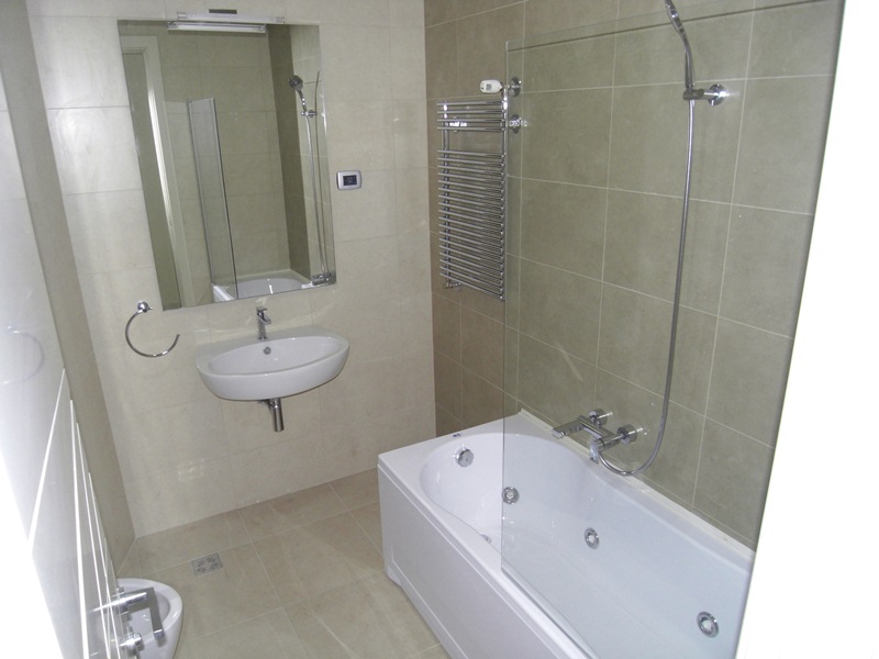 Modern bathroom with a jacuzzi and tiled walls in an apartment in Budva, Montenegro. Sink, bidet, and mirror installed.