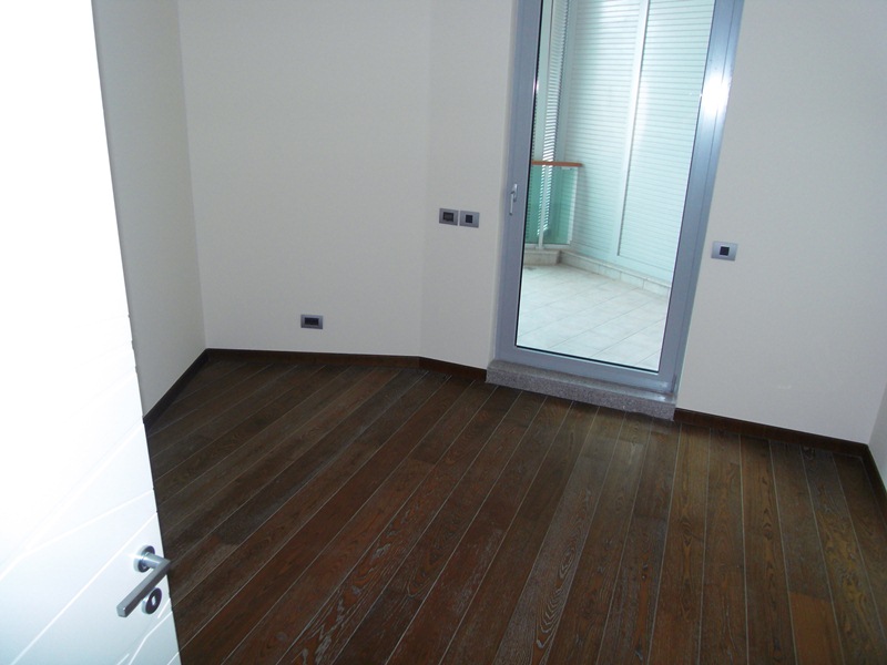 Bright bedroom with dark parquet flooring and access to a balcony in an apartment, Budva, Montenegro.