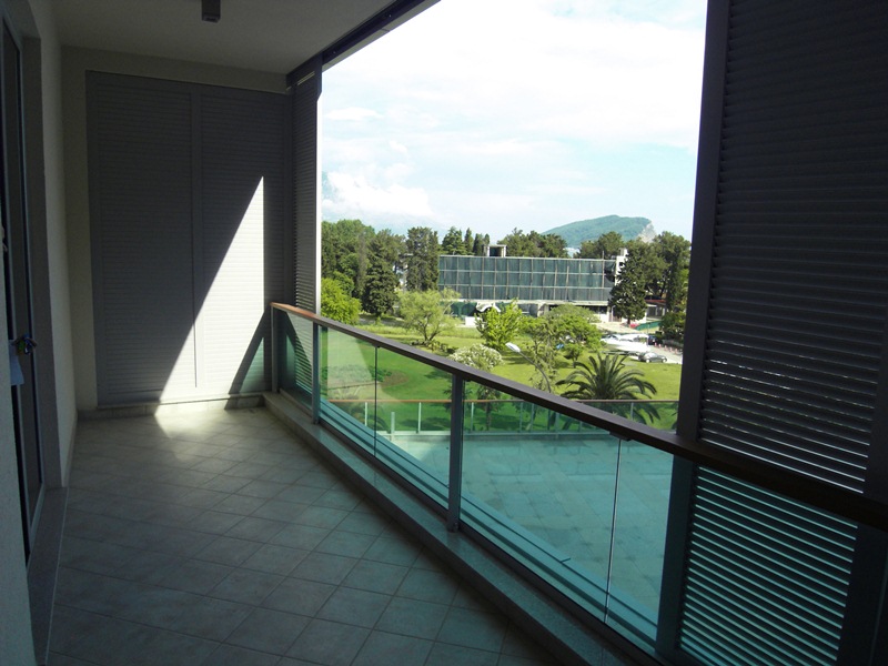 Spacious balcony with panoramic views of the park and mountains in an apartment in Budva, Montenegro, with modern finishes.