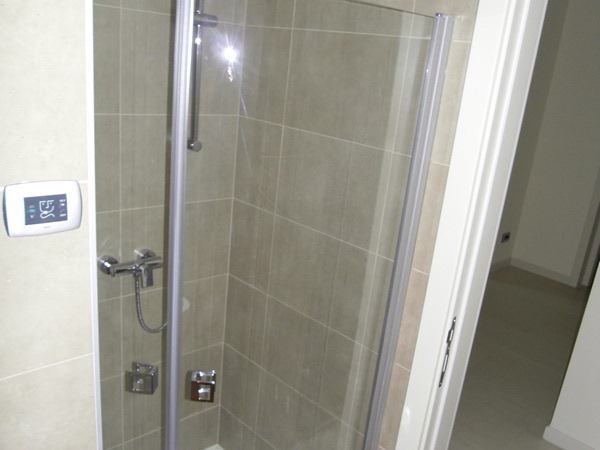 Modern shower cabin with beige tiles in the bathroom of an apartment in Budva, Montenegro.