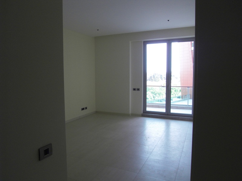 Bright living room in an apartment in Budva, Montenegro: panoramic window, access to the balcony, and modern tile finishes.