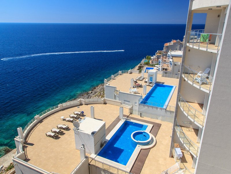 View of the outdoor pools and terrace with sun loungers by the sea in a residential complex, Dobri Vody, Montenegro.