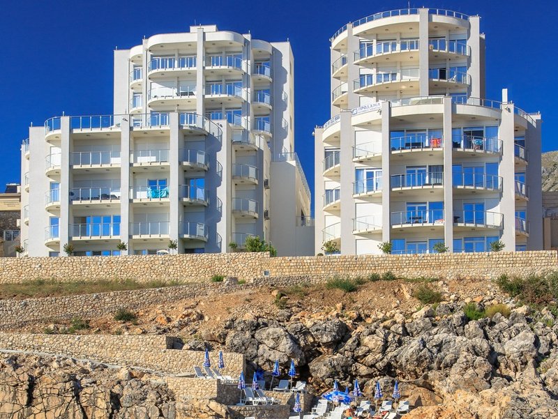 Modern residential complex with panoramic balconies by the sea in Dobra Voda, Montenegro: view of the facade and rocky beach.