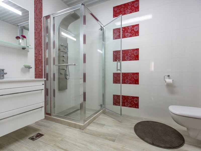 Modern bathroom with a shower cabin in an apartment, Dobri Vody, Montenegro: white tiles with red decor.