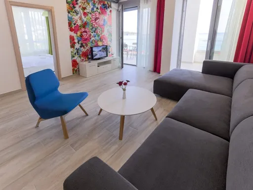 Living room with gray sofa, blue chair, white table, and floral wall mural near balcony doors.