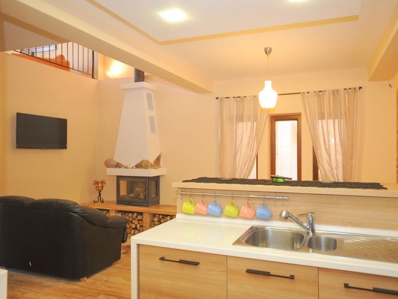 Kitchen-living room interior with a fireplace and a black sofa in a villa in Bigovo, Montenegro. Modern finishes and a cozy design.