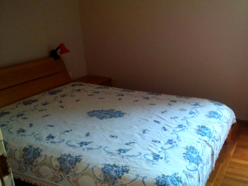 Bedroom with a double bed and wooden headboard in an apartment, Budva, Montenegro.