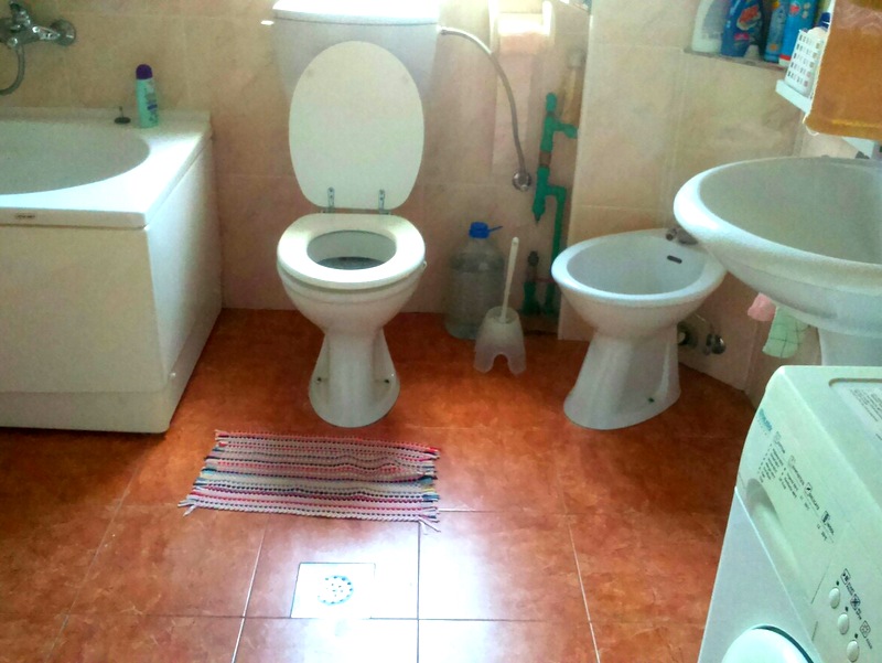 Bathroom in an apartment in Budva, Montenegro: tile, bathtub, toilet, bidet, sink, and washing machine.