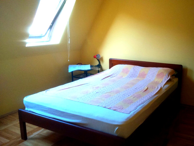 Bedroom with a double bed and a skylight in an apartment, Budva, Montenegro. Yellow walls and parquet flooring.