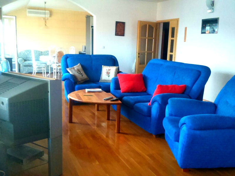 Living room with blue upholstered furniture and wooden flooring in an apartment for sale in Budva, Montenegro.