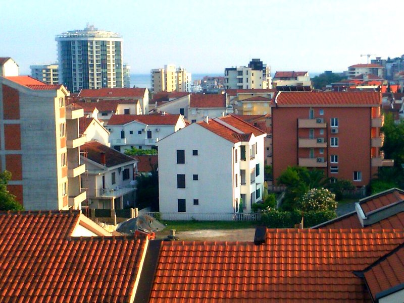 Panoramic view of a residential квартал with red tile roofs and modern houses in Budva, Montenegro.