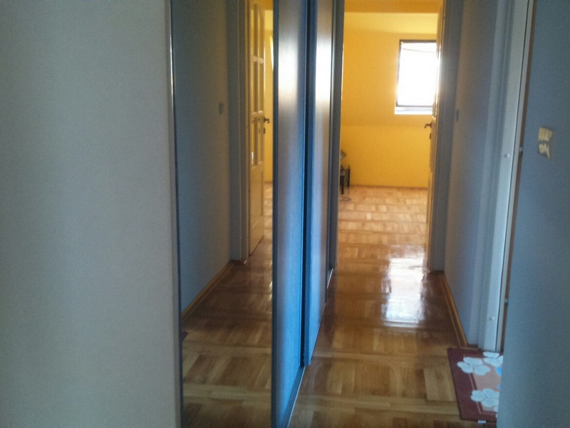 Bright hallway with a mirrored sliding wardrobe and parquet flooring in an apartment, Budva, Montenegro.