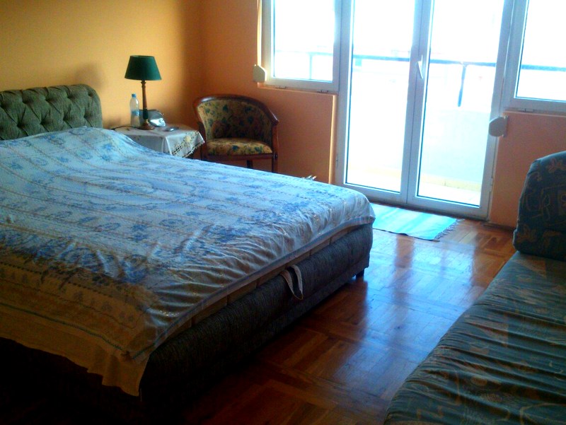 Bedroom in an apartment in Budva, Montenegro: double bed, parquet floor, access to the balcony, and an armchair.