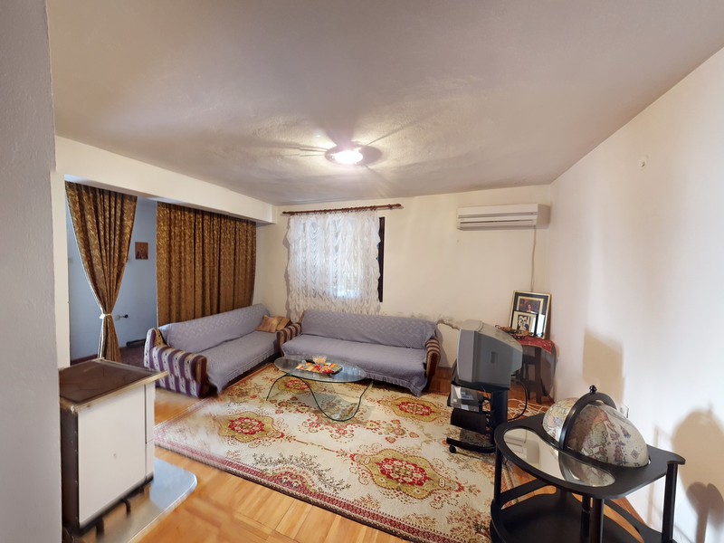 Living room in a house in Shushan, Montenegro: two sofas, a patterned rug, a stove, and a TV in the interior.