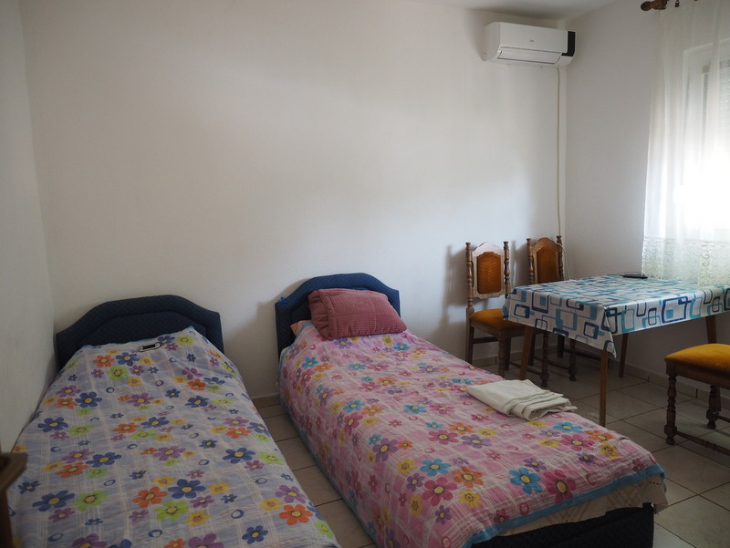 Bedroom with two beds, a dining table, and air conditioning in a house for sale, Bar, Montenegro.