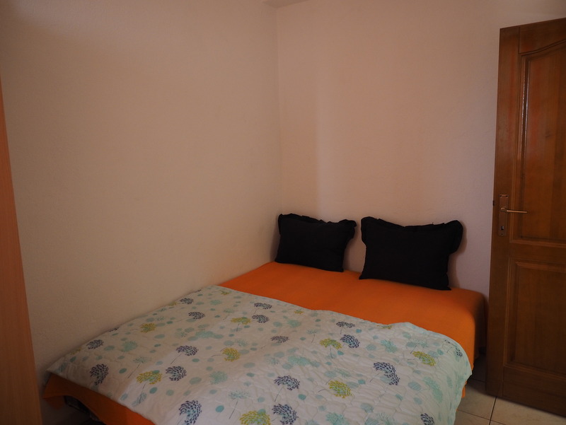 Cozy bedroom with a double bed in a house for sale in Bar, Montenegro: light walls and a wooden door.