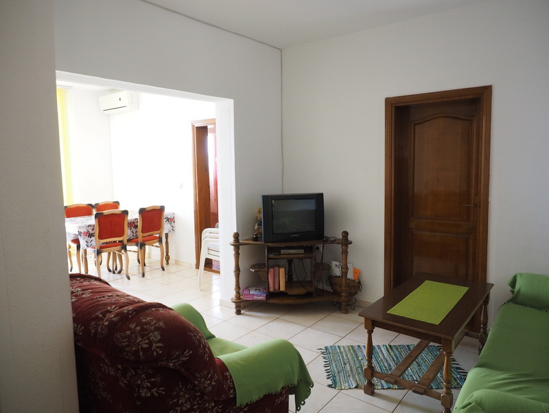 Living room with soft seating and dining area in a house for sale, Bar, Montenegro. Bright interior with tile flooring.