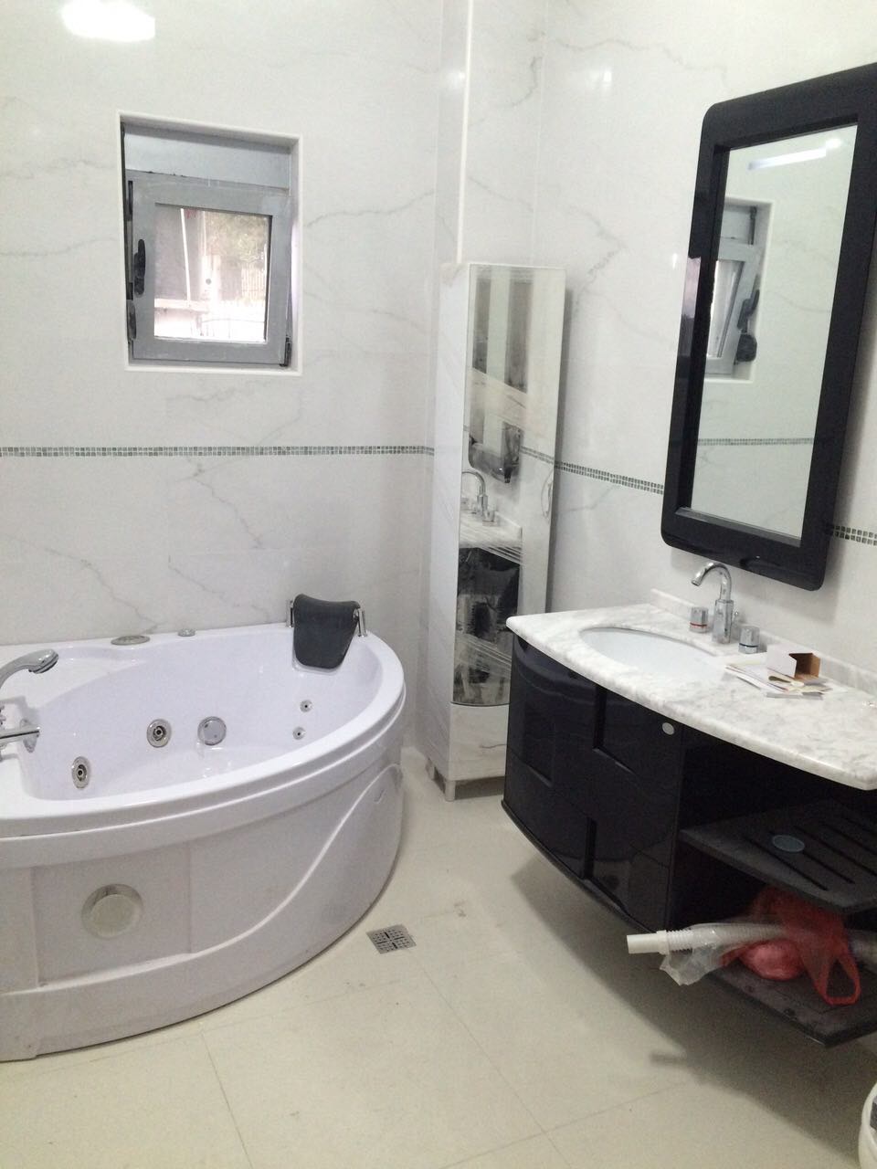 Bathroom with a jacuzzi and black furniture in a house, Shushan, Montenegro. Light marble-look tiles, modern interior.