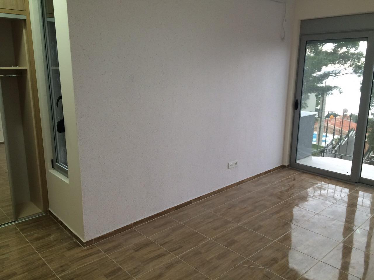 Bright living room in a house in Shushan, Montenegro: tiled floor, built-in wardrobe, and access to a balcony with sea view.