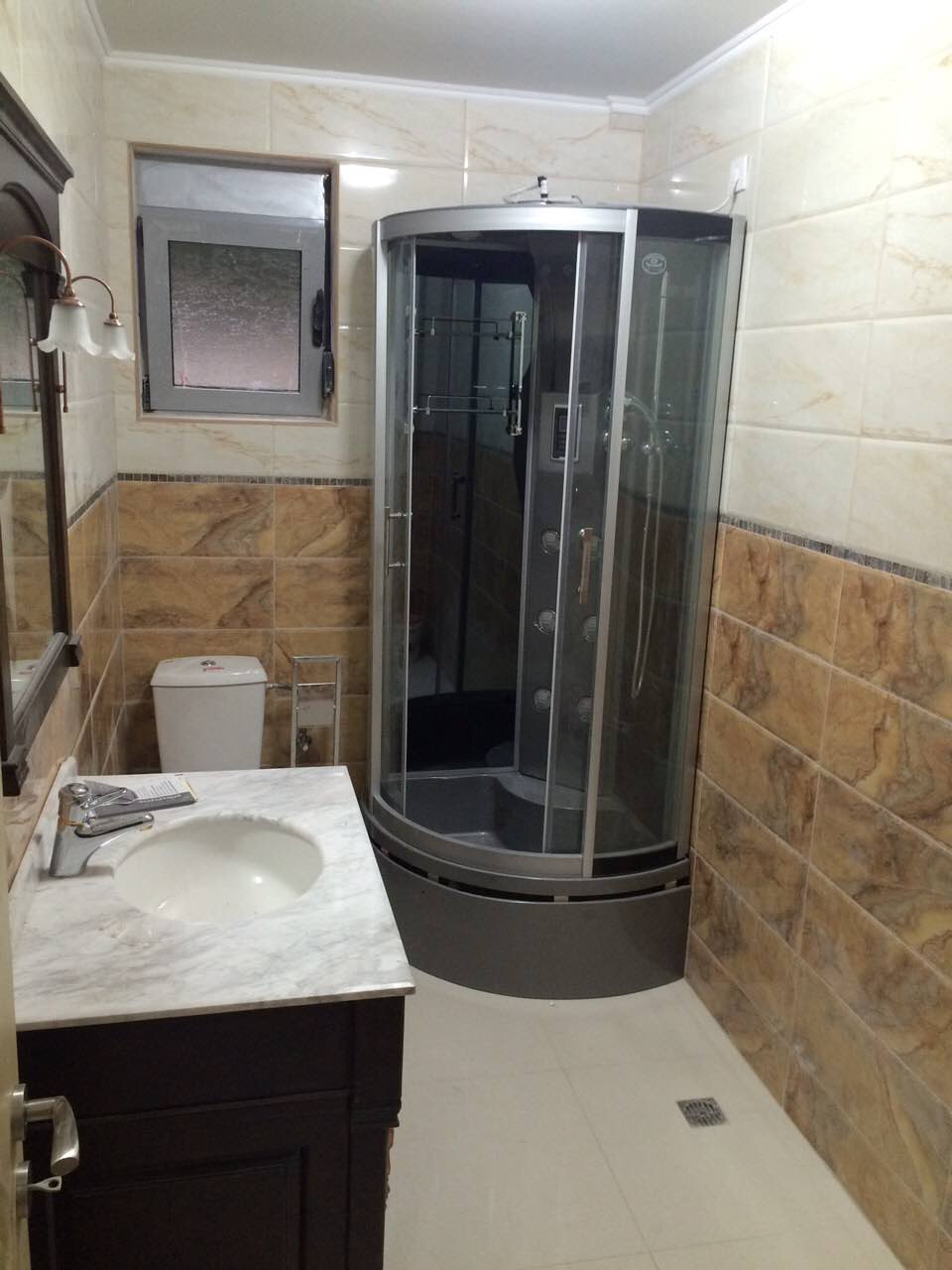 Bathroom in a house, Shushan, Montenegro: shower cabin, vanity with marble countertop, and light wall tiles.