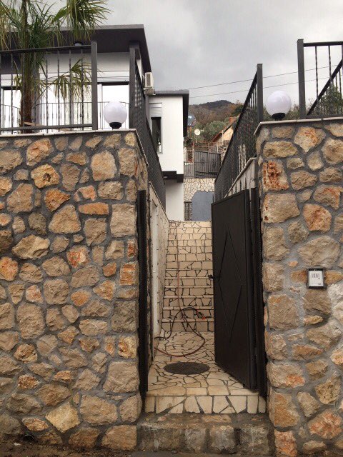 Entrance to a house in Shushan, Montenegro: stone facade cladding, natural stone stairs, and a modern gate.