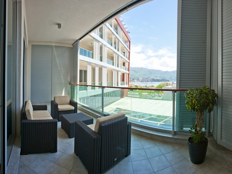 Terrace with wicker furniture in an apartment in Budva, Montenegro, with panoramic sea and mountain views.