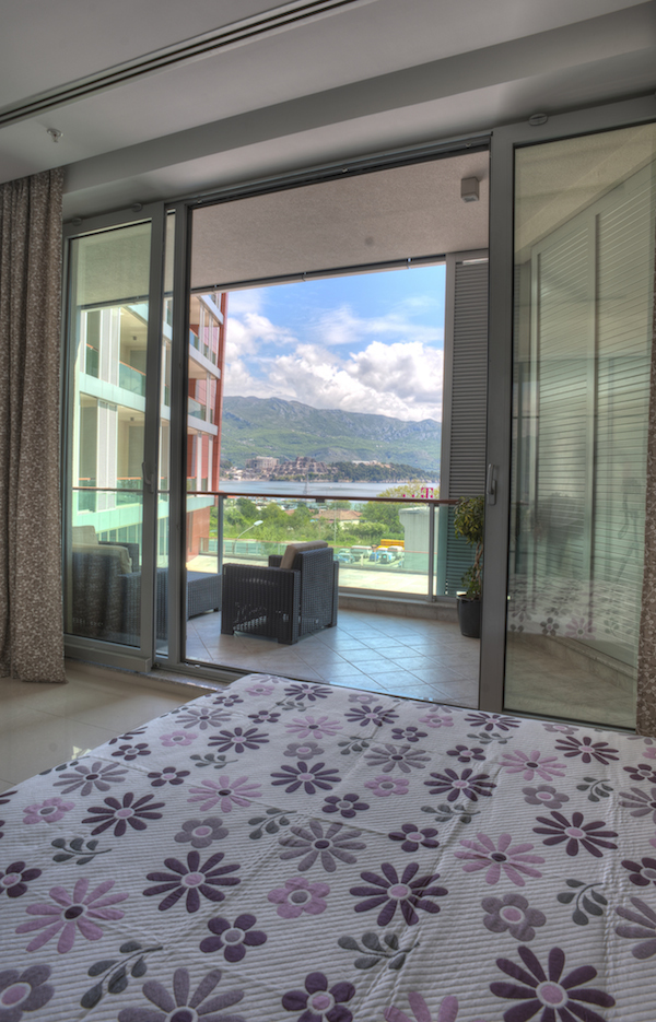 Bedroom in an apartment in Budva, Montenegro, with panoramic views of the sea and mountains and access to a furnished terrace.