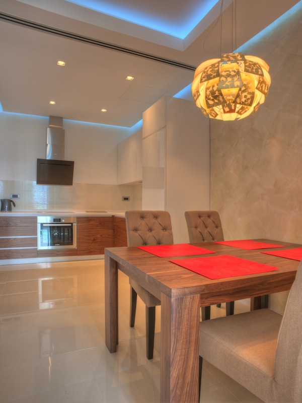 Modern kitchen-dining room in an apartment in Budva, Montenegro: wooden cabinetry, dining area, and designer lighting.