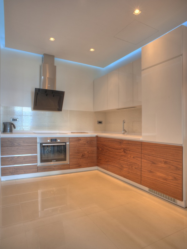 Modern kitchen in an apartment in Budva, Montenegro: glossy fronts, built-in appliances, and ceiling lighting.