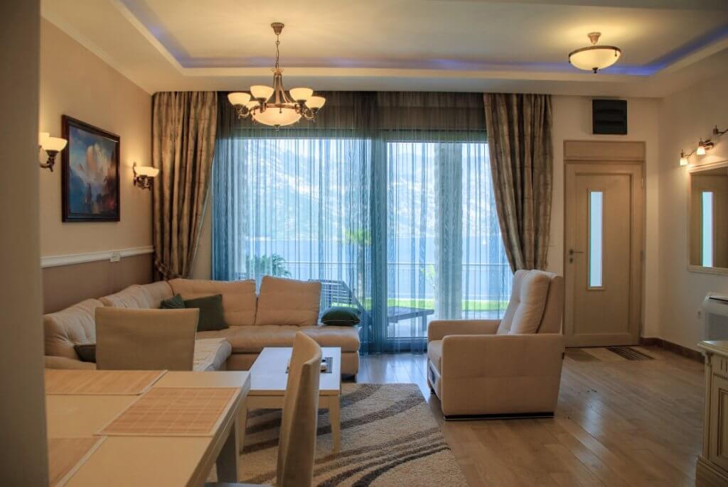 Cozy living room with soft furniture and sea view in an apartment in Kostanica, Montenegro. Modern interior with a terrace.