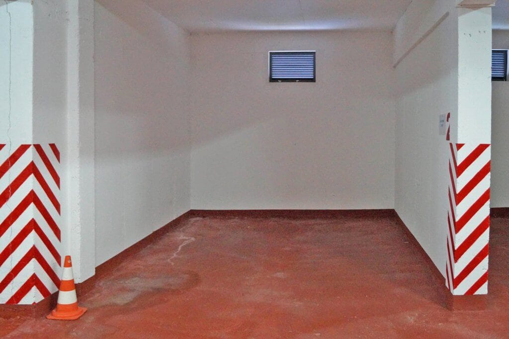 Parking space in the underground garage of a residential complex in Kostanica, Montenegro, with a concrete floor and markings.