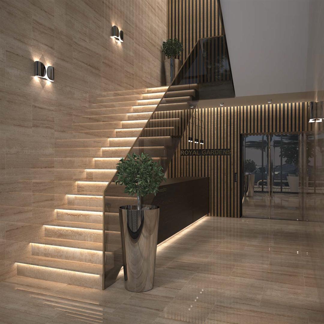 Modern lobby interior of the Royal Gardens residential complex in Budva, Montenegro: staircase with lighting and stone finishes.