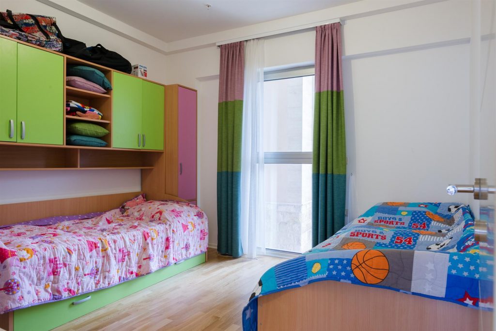 Children's bedroom with two beds and bright furniture in an apartment in Becici, Montenegro.