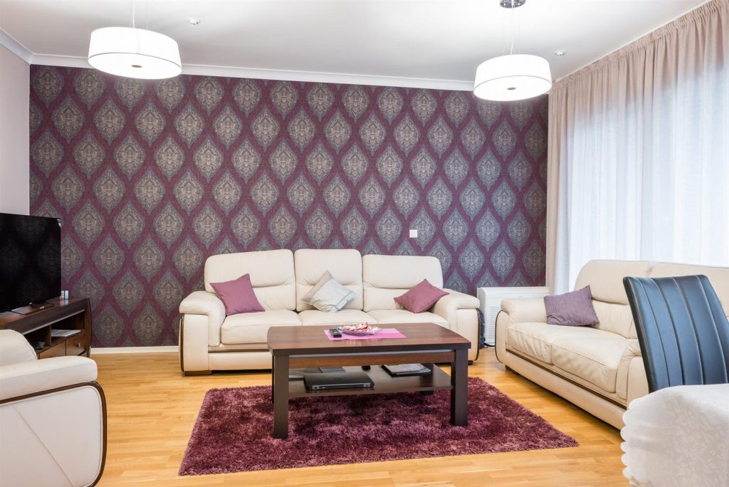Living room in an apartment in Bečići, Montenegro: light leather sofas, a coffee table, and an accent wall with a pattern.