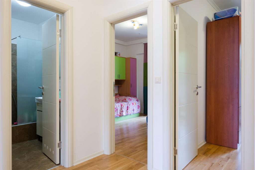 Hallway in an apartment in Bečići, Montenegro: view of the bathroom and children's bedroom with furniture and parquet flooring.