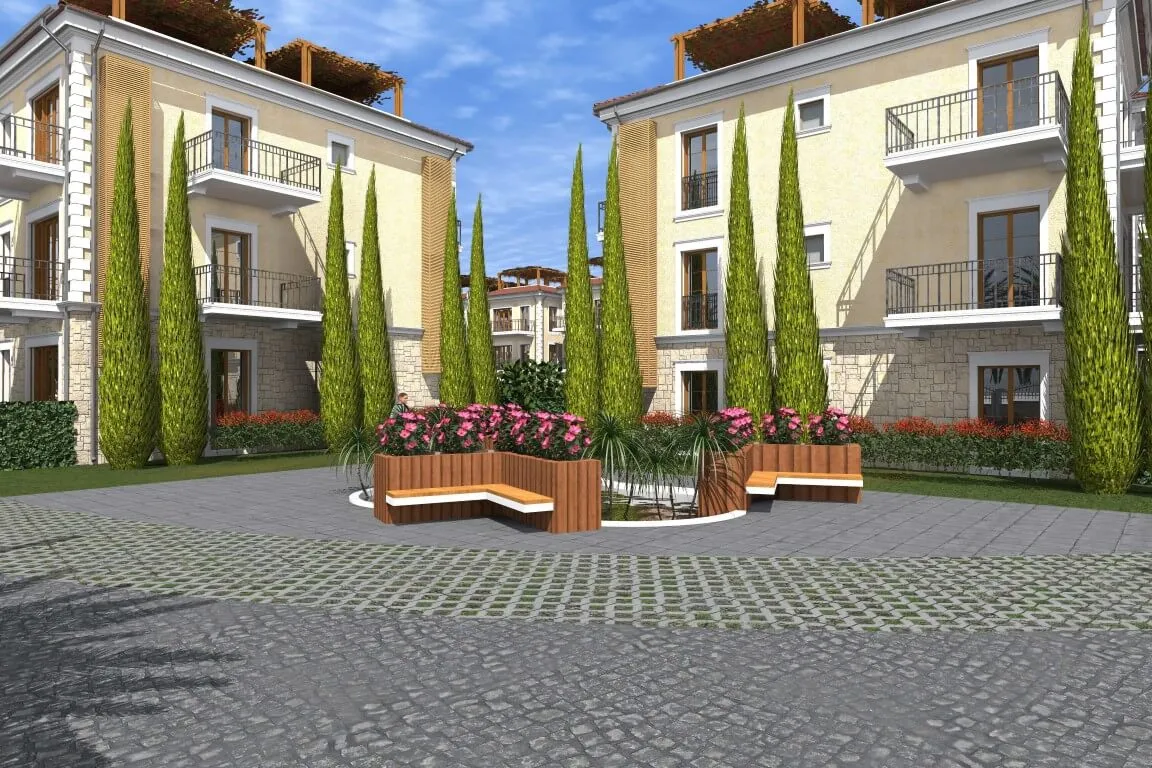 Exterior view of a residential complex courtyard featuring wooden benches, flower beds, and tall cypress trees between buildings.