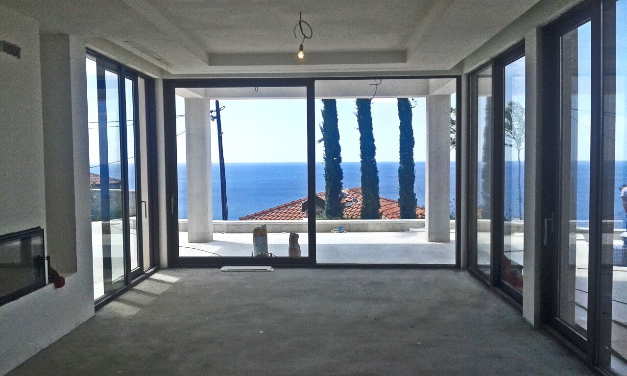 Living room with panoramic windows and sea view in an under-construction villa in Reževići, Montenegro.