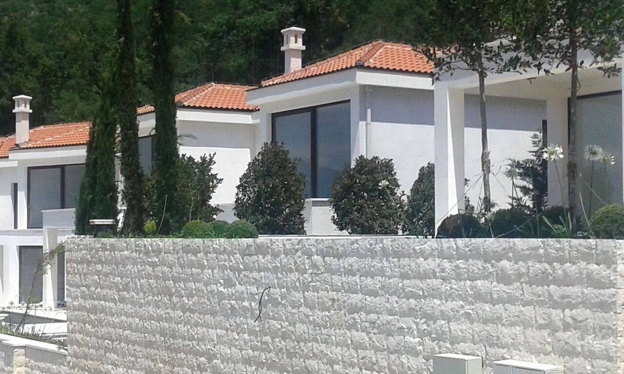 Modern villas with tiled roofs and a stone fence in Reževići, Montenegro, front and landscape view.