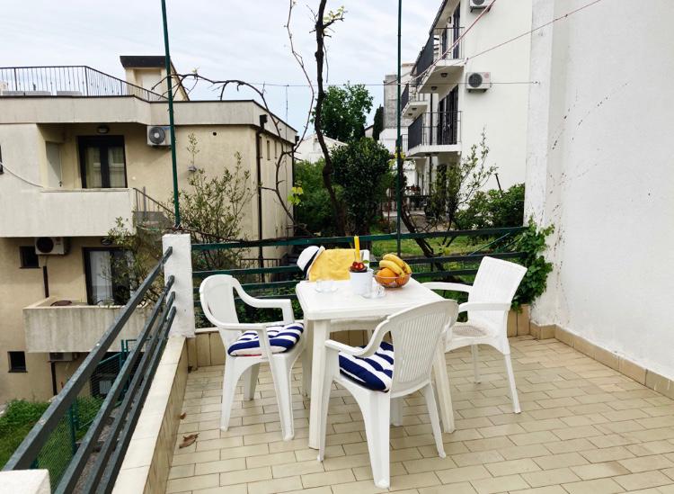 Cozy terrace with plastic furniture and a city view at a hotel in Budva, Montenegro. Balcony with tile and greenery.